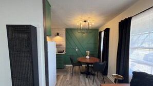 Ein kompakter Wohnbereich mit einer Küchenzeile, einer Essecke mit rundem Tisch und Stühlen sowie einer Sitzecke mit einer Couch.