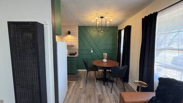 A compact living space with a kitchenette, a dining area with a round table and chairs, and a seating area with a sofa.
