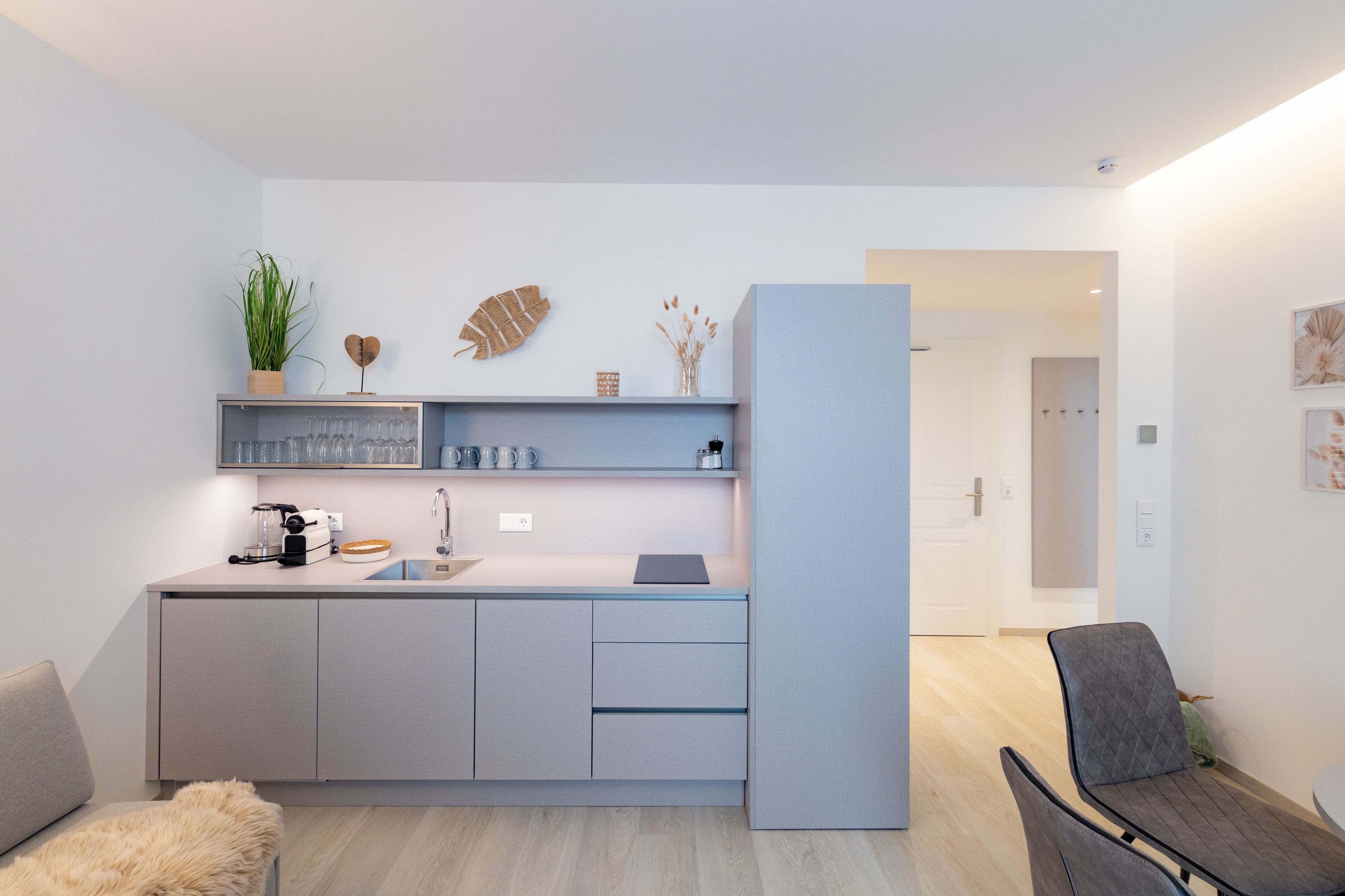 A modern kitchen with a built-in dishwasher, a sink, and a countertop with various items.