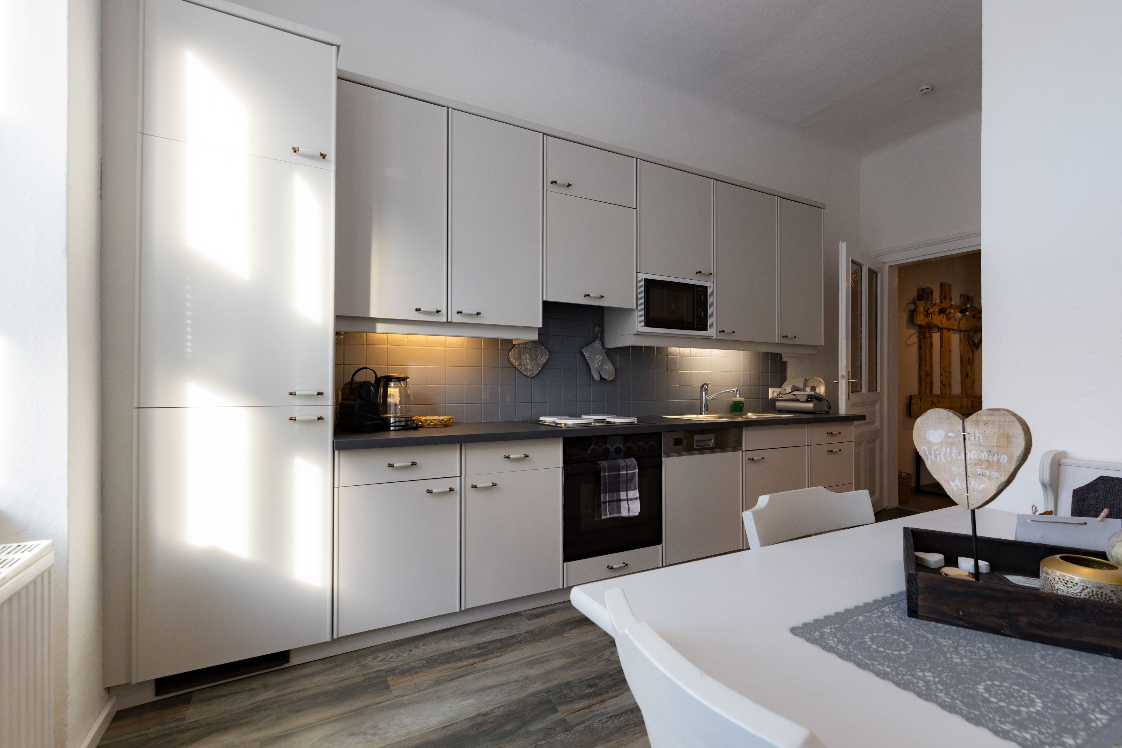 A modern kitchen with white cabinetry, a microwave, and a coffee maker.