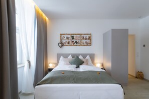 A hotel room with a bed, a bedside table, a wall-mounted photo collage, and a window with curtains. - Mohr am Semmering (Semmering)