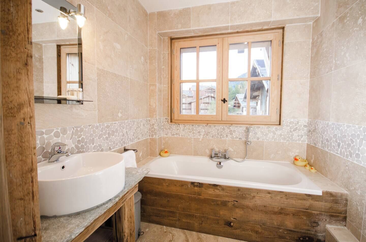 Ein Badezimmer mit einem Holzbadezimmer, zwei Waschbecken, einer Badewanne und einem Fenster mit Blick auf Häuser.