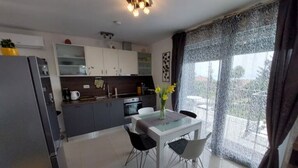 Eine moderne Küche mit Essbereich, Kühlschrank, Schränken und einem Fenster mit Vorhängen.
