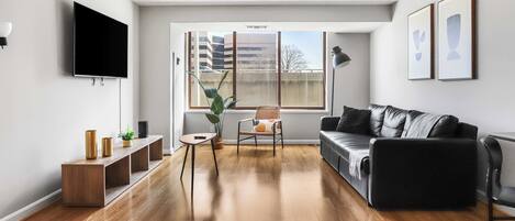 A modern living room with a flat-screen TV, a sofa, a coffee table, and a chair.