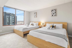 A hotel room with two beds, large windows, and artwork on the walls. - Apartment Steps from Pentagon City Metro (Arlington)