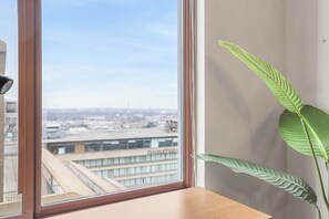 Ein Zimmer mit einem großen Fenster, einem Holztisch und einer Topfpflanze.