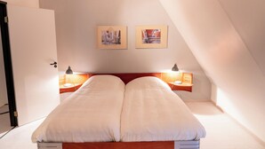 A bedroom with a double bed, two bedside tables with lamps, and two framed pictures on the wall. - Maison 2 du domaine d'embourg (Souvigny)