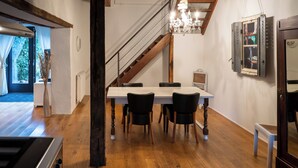 A dining area with a wooden table and chairs, a chandelier, and a staircase. - Maison 2 du domaine d'embourg (Souvigny)