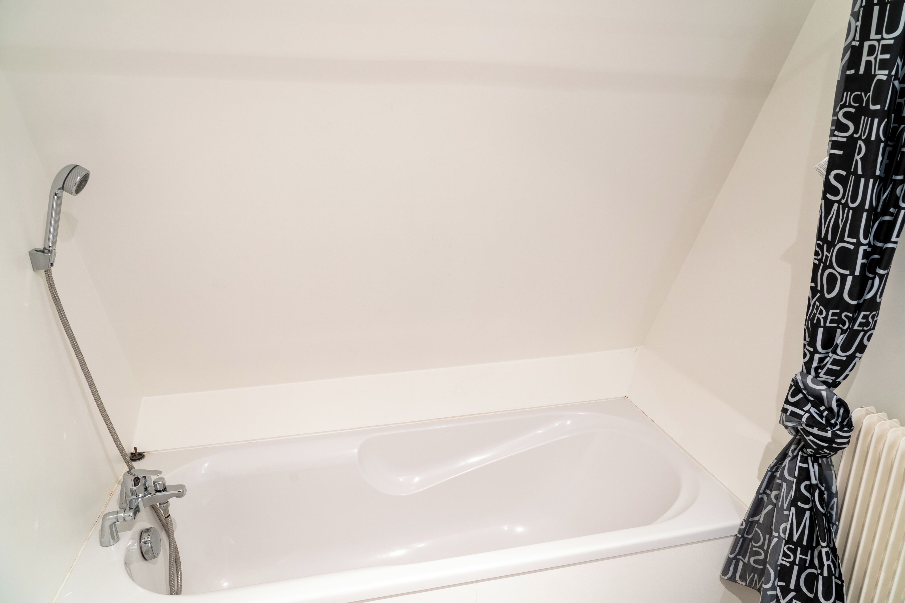 A bathroom with a white bathtub, a showerhead, and a towel with text.