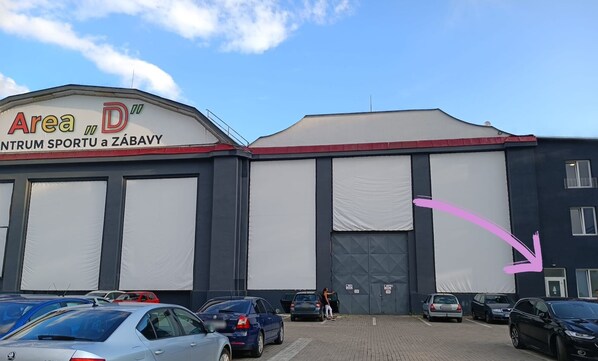 A building with a sign reading 'Area D INTRUM SPORTU a ZÁBAVY' and a large covered entrance. - Apartmány Plzeň Zborovská (Plzeň)