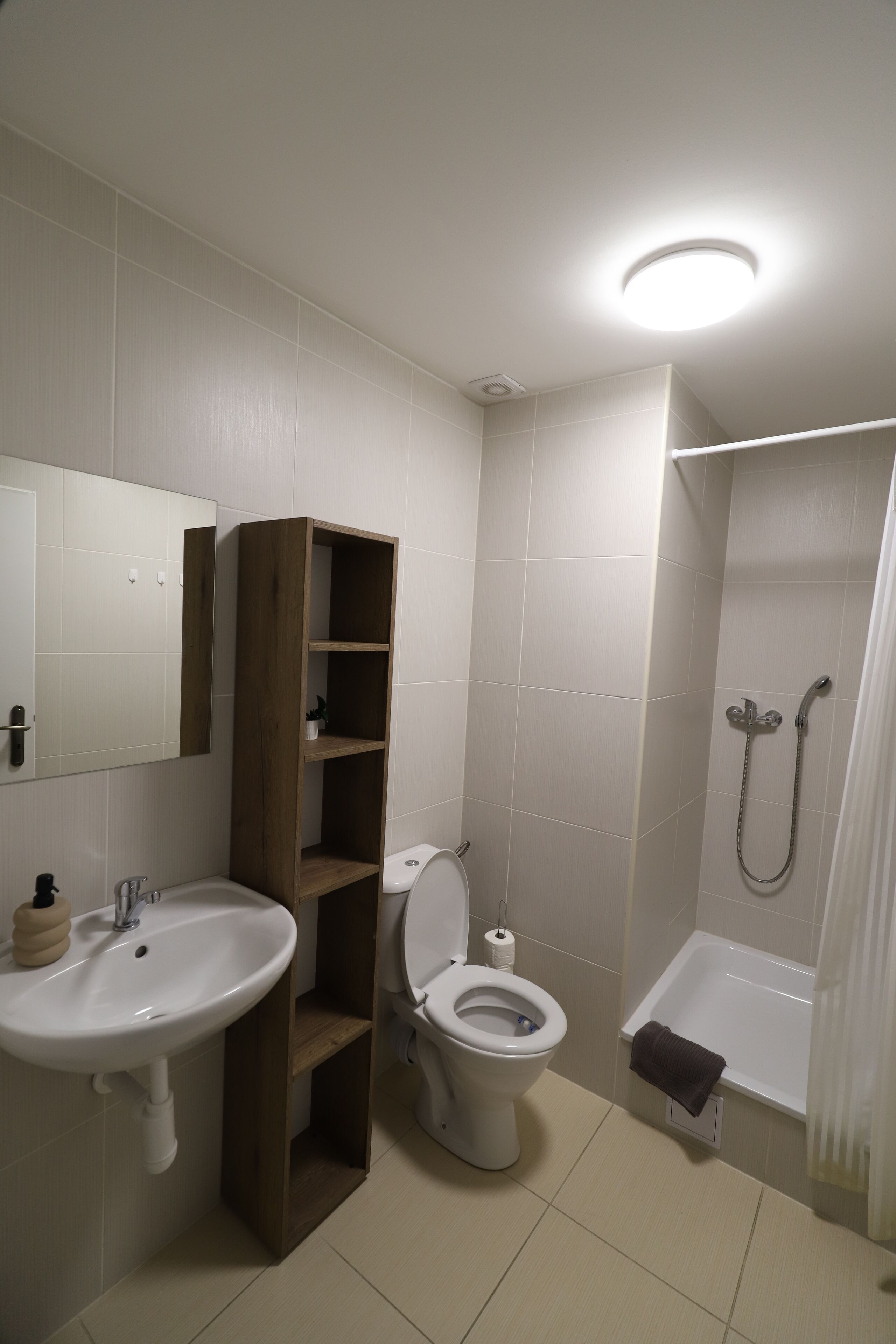 Een badkamer met een wastafel, toilet, douche en een houten schapunit.