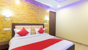 A neatly made bed with a red and white bedspread, a wooden headboard, and two red pillows. - Hotel O Red Stone (New Delhi)