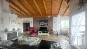 A living room with a fireplace, a television, a sofa, and a coffee table. - Apartment in Traditional Timber-Framed House with Garden in the Bergisches Land (Overath)