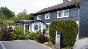 A modern two-story house with a dark exterior, white trim, and a well-maintained garden. - Apartment in Traditional Timber-Framed House with Garden in the Bergisches Land (Overath)
