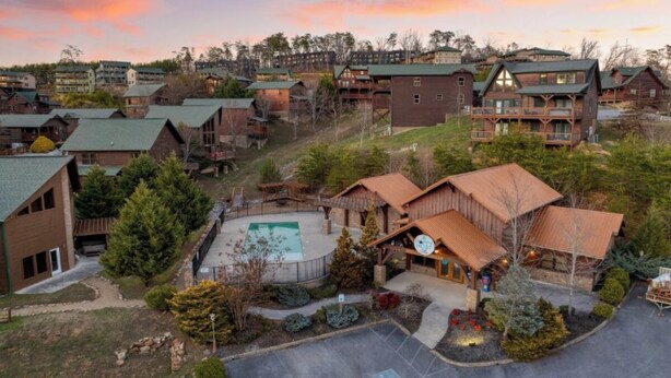 Ein Resort mit mehreren Holzhütten, einem zentralen Gebäude mit Schwimmbad und einer hügeligen Landschaft im Hintergrund.