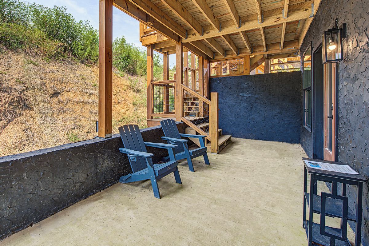 A covered outdoor area with Adirondack chairs, a staircase, and a view of the surrounding landscape.