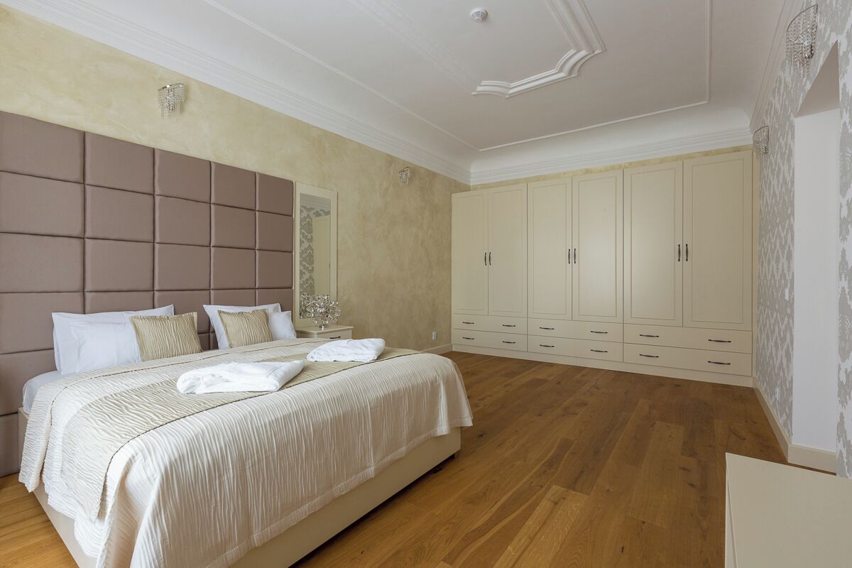 A bedroom with a large bed, a chest of drawers, and a wardrobe.