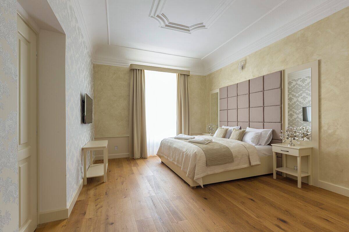 A bedroom with a bed, bedside tables, a mirror, and a television.