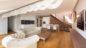 En modern loftlägenhet med en sovplats på entresolplan, ett matområde, ett kök och en trappa.