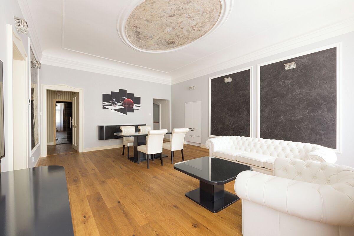 A modern living room with a white sofa, a black coffee table, and a dining area with a white table and chairs.