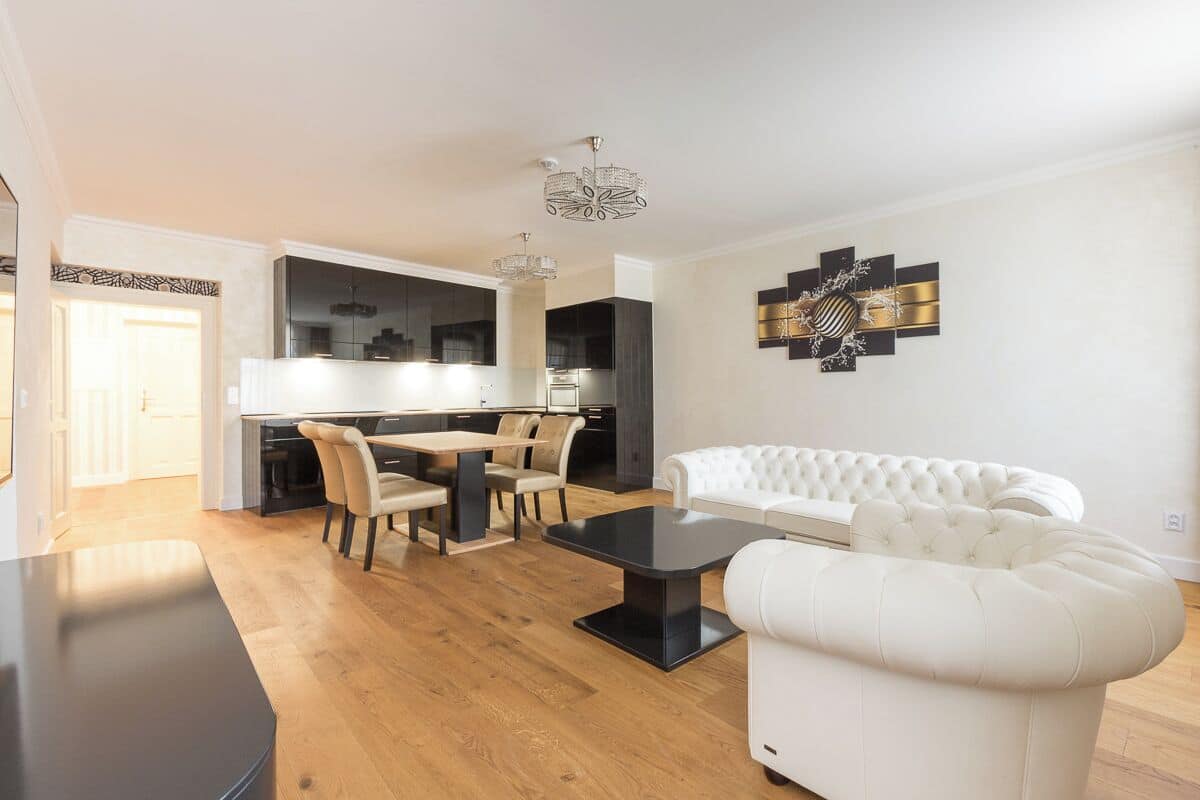 A modern living room with a dining area, a white sofa, and a black coffee table.