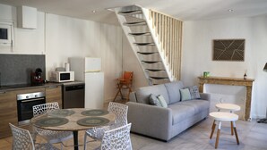 A modern kitchen with a dining area, a staircase, and a living room with a sofa and coffee table. - Le Cocon St Martin – Cozy Duplex in Nevers City Center, Air Conditioning (Nevers)