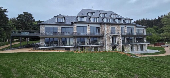 A multi-story house with a stone facade, large windows, and a balcony. - Le Panoramic Garabit (Anglards-de-Saint-Flour)