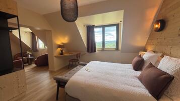 A bedroom with a large bed, a desk, and a chair, a window with curtains, and a hanging light fixture.