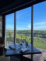 Una mesa de comedor con vistas a un paisaje boscoso a través de amplias ventanas.