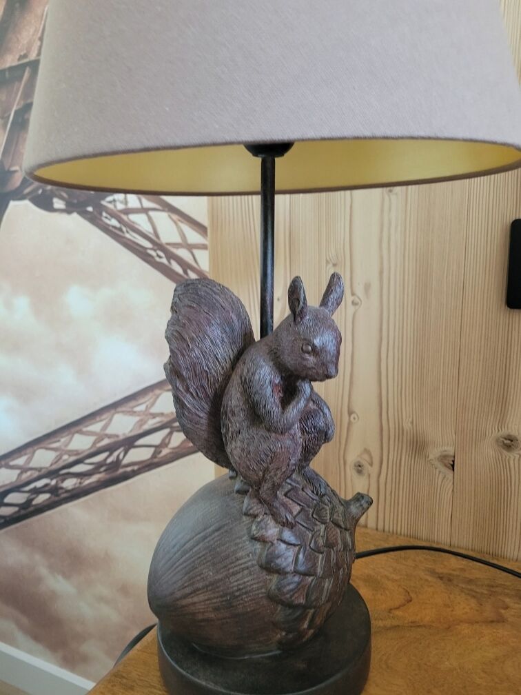 A lamp with a squirrel figurine on a wooden base.