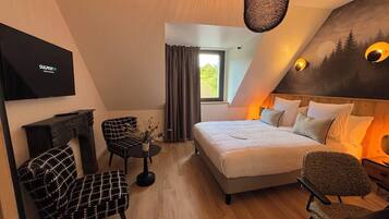 Un dormitorio moderno con cama, dos sillones, una mesita, chimenea y televisor.