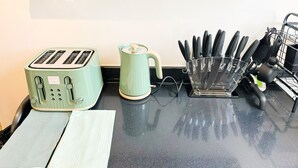 Een aanrecht met een groene toaster, een waterkoker en een messenhouder.
