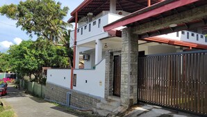 A two-story house with a red roof, white walls, and a stone pillar.