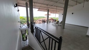 A spacious indoor area with a balcony, a staircase, and a view of the outdoors.