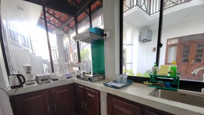 A kitchen with dark wooden cabinets, a white countertop, and a window overlooking a street.