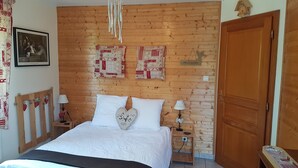 A bedroom with a wooden headboard, a bed with white bedding, two bedside tables with lamps, and a framed picture on the wall.