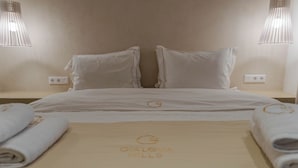 En snyggt bäddad säng med en handduk och en skylt med texten "GIALSVA HILLS" i ett hotellrum.