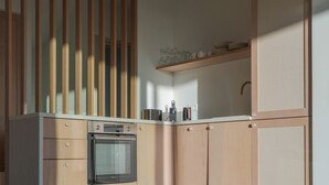 Ett modernt kök med träskåp, en inbyggd ugn och en hylla med glasvaror.