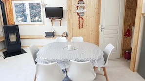 Ein Essbereich mit einem runden Tisch, weißen Stühlen, einem Fernseher und einem Kamin.