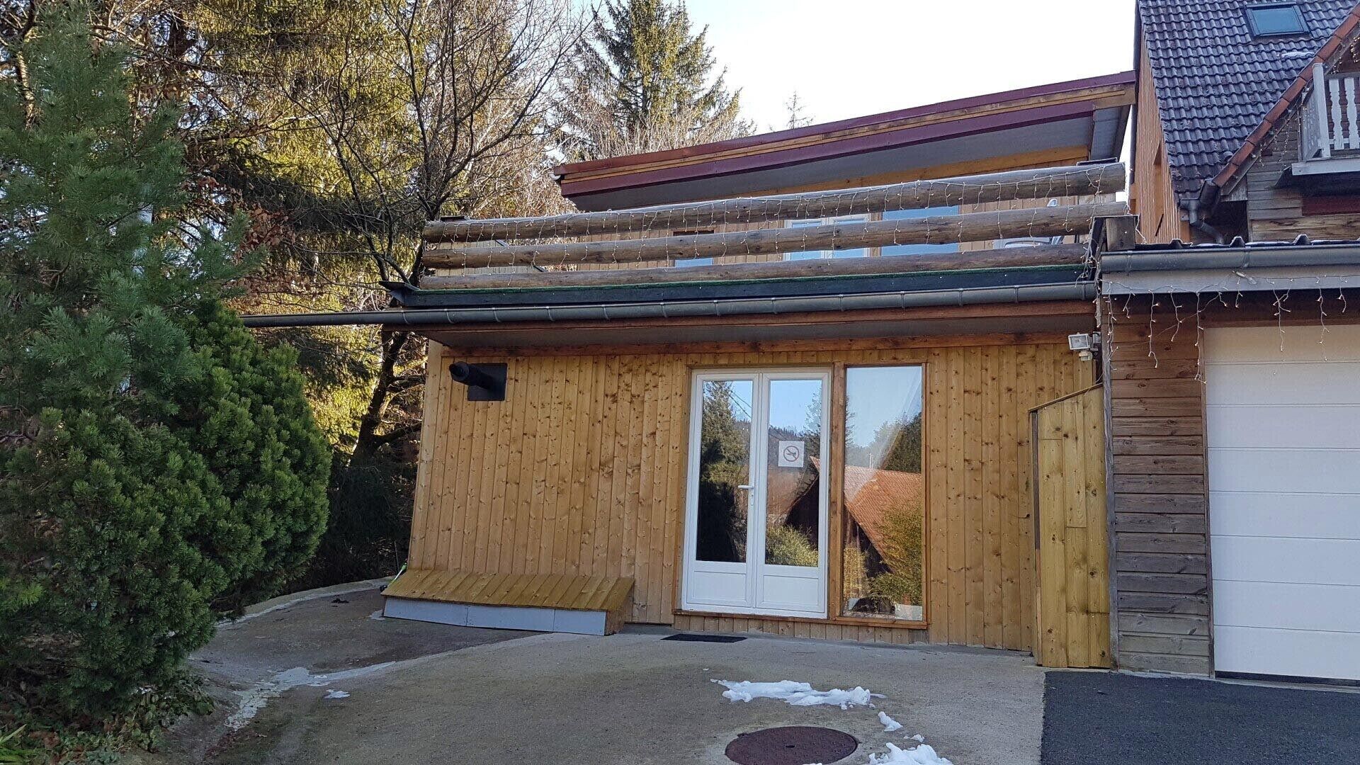 Una baita in legno con una porta vetrata, un piccolo oblò e un basculante per garage.