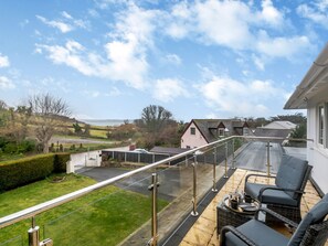 A balcony with a glass barrier, outdoor seating, and a view of the surrounding landscape. - Broadsands (Paignton)