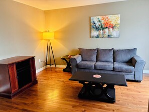 A living room with a sofa, a coffee table, a lamp, and a cabinet.