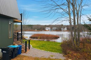 Une propriété située au bord d’un lac, dotée d’un quai, d’une pelouse et d’un bâtiment avec une véranda.