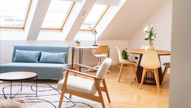 Un salon moderne avec un canapé, une table à manger, des chaises et une lucarne.