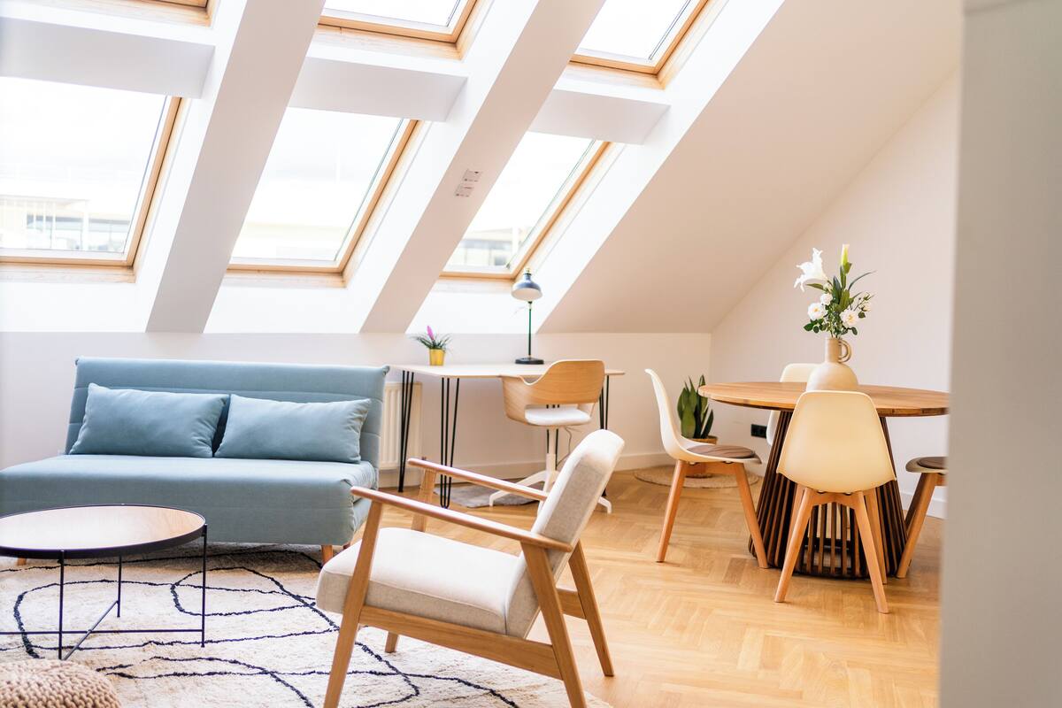 Ein modernes Wohnzimmer mit einer Couch, einem Esstisch, Stühlen und einem Oberlicht.