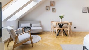 Une chambre de style loft moderne, avec un plafond en pente, un canapé, une table à manger avec des chaises et une petite plante en pot.