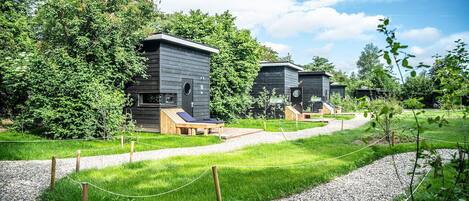 A row of modern cabins with wooden exteriors, each featuring a small deck and a window.