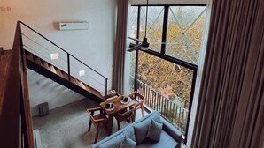 A modern interior with a staircase leading to a balcony, a sofa, and a dining table. - Two bedroom  in Mexico, Tulum (Tulum)