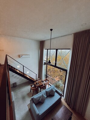 Ein modernes Interieur mit einer Treppe zu einem Balkon, einer Couch und einem Esstisch.