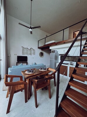 Ein moderner Wohnraum mit Essbereich, einer Couch, einem Fernseher und einer Treppe.